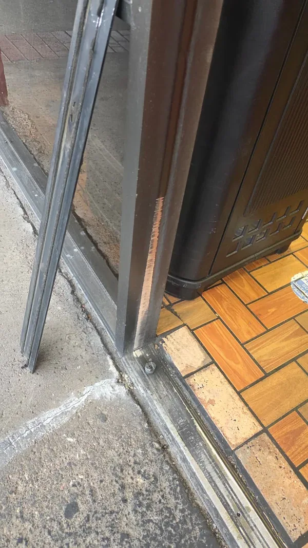 Lower door-frame corner meeting the storefront threshold