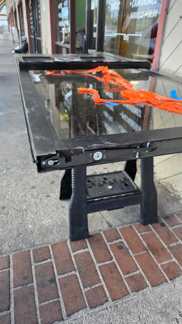 Removed commercial glass door panel resting on work stands