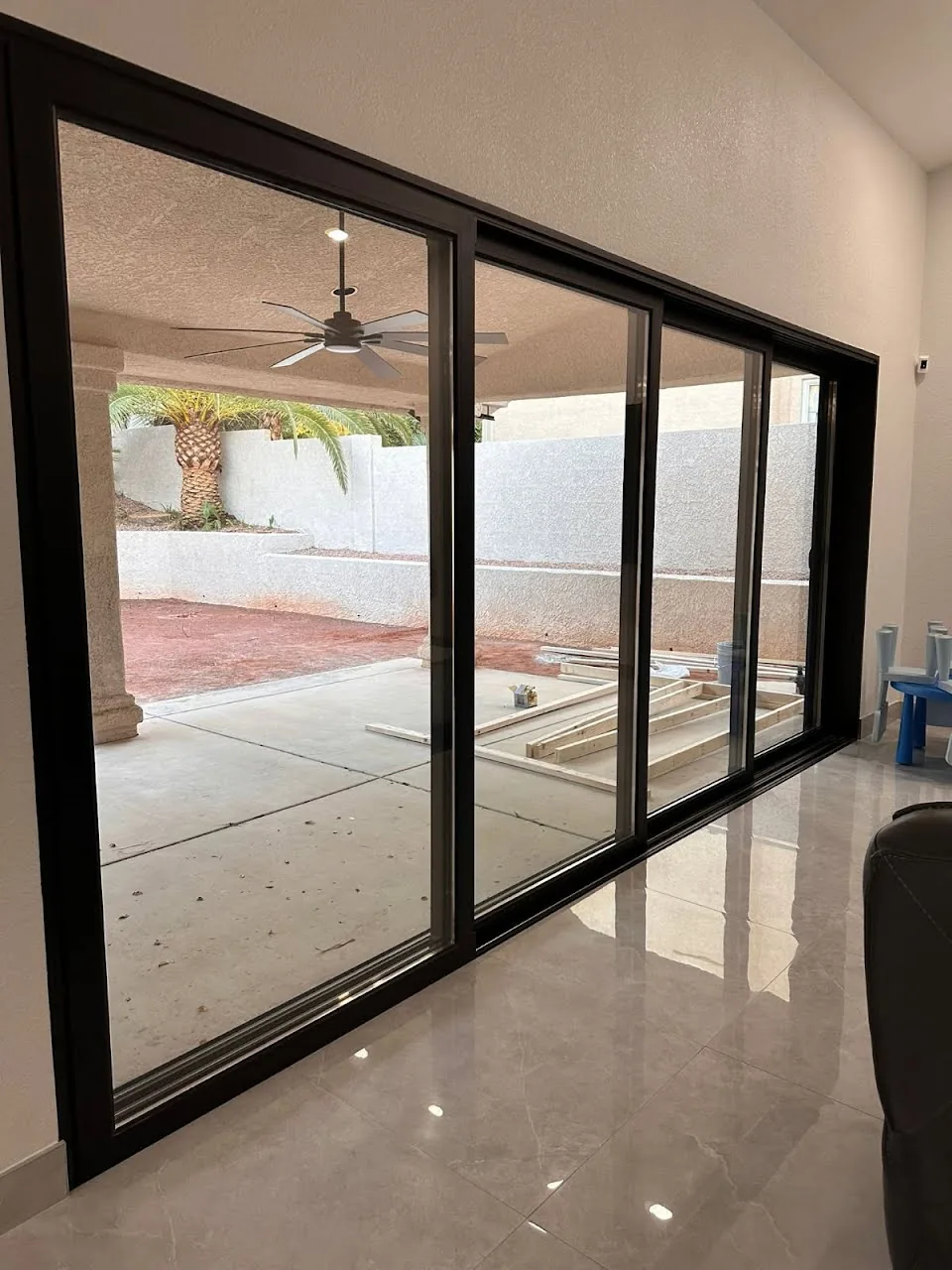 Black-framed multi-panel patio door beside a tiled floor and covered patio