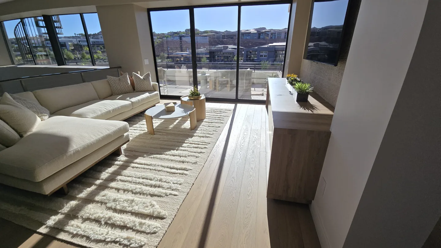 Living room with dark-framed sliding glass doors facing a furnished balcony